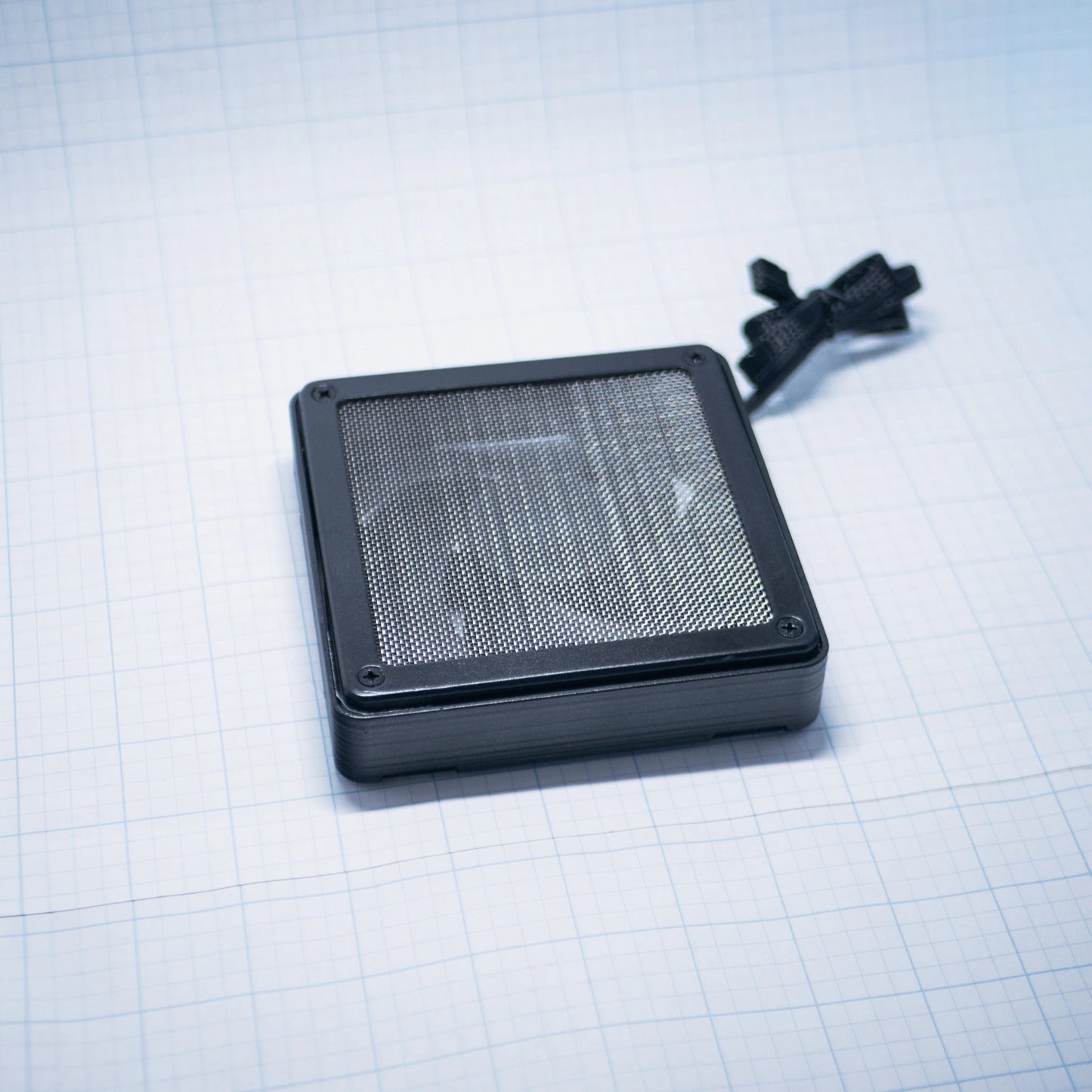 Black shell with raw steel mesh - 120mm Fan Shroud Filter & Outer Cover lying flat against white background with grid pattern. 